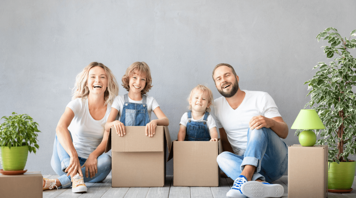 happy family smiling in moving boxes-best charlotte home loans blog