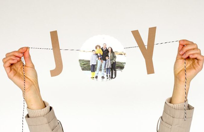 Holiday bunting that says "JOY" with a picture of a family in the "O"